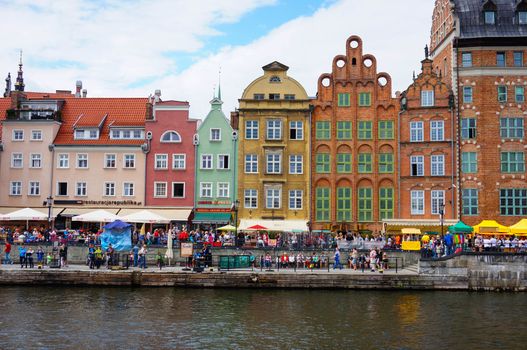 GDANSK, POLAND - JULY 29, 2015: People sitting by a river next to buildings