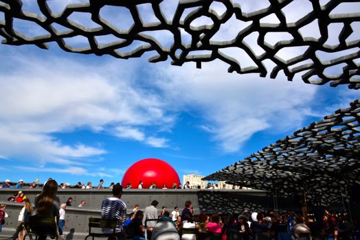 FRANCE, Marseille : This picture taken on September 19, 2015 in Marseille, shows a red ball on the roof of Mucem museum. New York based artist Kurt Perschke's RedBall project stopped off in Marseille between September 19 and 25, 2015. The project involves installing a five meter wide red ball in different places from town to town. 
