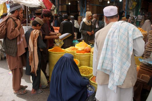 AFGHANISTAN, Kandahar: Crowds are out shopping in Charso Bazaar for Eid on September 22, 2015. Men in traditional dress and women in burqas buy dried fruits, biscuits, clothes, shoes, hats and things for their homes in Charso Bazaar, Kandahar. 