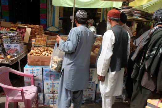 AFGHANISTAN, Kandahar: Crowds are out shopping in Charso Bazaar for Eid on September 22, 2015. Men in traditional dress and women in burqas buy dried fruits, biscuits, clothes, shoes, hats and things for their homes in Charso Bazaar, Kandahar. 