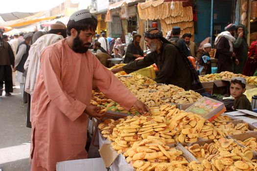 AFGHANISTAN, Kandahar: Crowds are out shopping in Charso Bazaar for Eid on September 22, 2015. Men in traditional dress and women in burqas buy dried fruits, biscuits, clothes, shoes, hats and things for their homes in Charso Bazaar, Kandahar. 