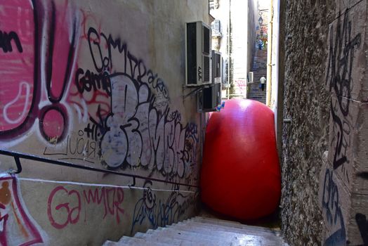 FRANCE, Marseille : This picture taken on September 19, 2015 in Marseille, shows a red ball on the stairs of a street in Marseille. New York based artist Kurt Perschke's RedBall project stopped off in Marseille between September 19 and 25, 2015. The project involves installing a five meter wide red ball in different places from town to town. 
