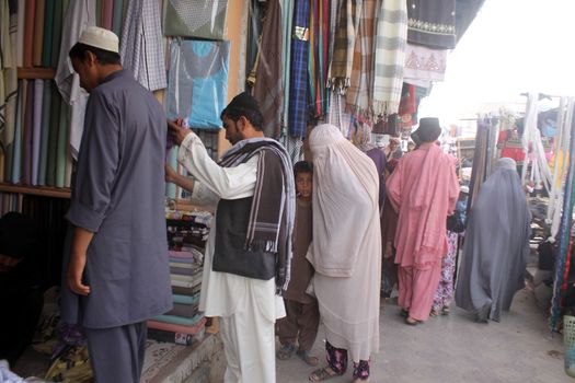 AFGHANISTAN, Kandahar: Crowds are out shopping in Charso Bazaar for Eid on September 22, 2015. Men in traditional dress and women in burqas buy dried fruits, biscuits, clothes, shoes, hats and things for their homes in Charso Bazaar, Kandahar. 