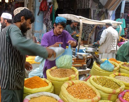 AFGHANISTAN, Kandahar: Crowds are out shopping in Charso Bazaar for Eid on September 22, 2015. Men in traditional dress and women in burqas buy dried fruits, biscuits, clothes, shoes, hats and things for their homes in Charso Bazaar, Kandahar. 