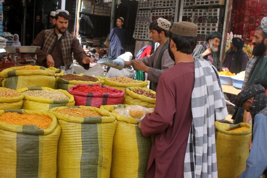 AFGHANISTAN, Kandahar: Crowds are out shopping in Charso Bazaar for Eid on September 22, 2015. Men in traditional dress and women in burqas buy dried fruits, biscuits, clothes, shoes, hats and things for their homes in Charso Bazaar, Kandahar. 