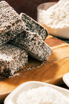 Group of Lamingtons on a timber cutting board with food ingredients in the background