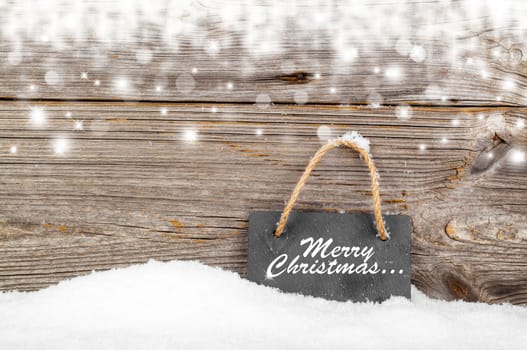 Black board of slate on old rustic wooden background, with snow