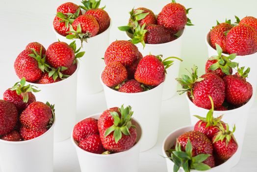 sweet ripe tasty rustic strawberries in white paper cups on the table