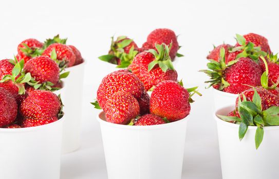 sweet ripe tasty rustic strawberries in white paper cups on the table