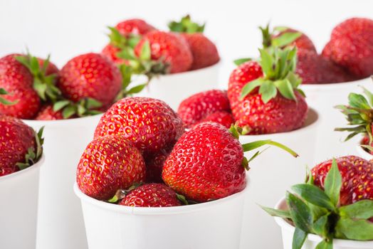 sweet ripe tasty rustic strawberries in white paper cups on the table