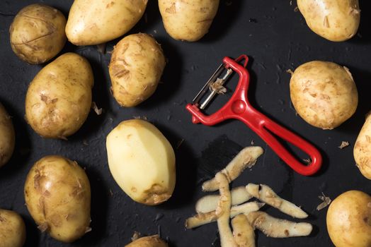 peeled potatoes, Vegetable peeler, raw potatoes and potato peels on black background, cooking potatoes