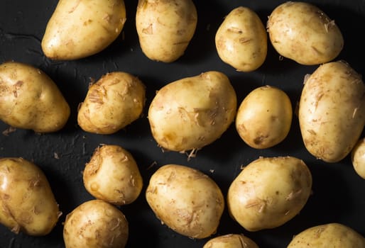  raw new potatoes on black background, cooking potatoes