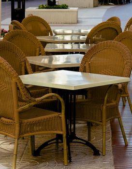 Elegant Street Cafe with Marble Tables and Wicker Chairs Outdoors. Focus on Foreground