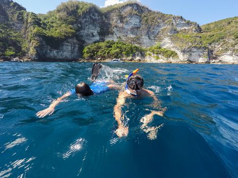 young boy snorkeling with father in a tropical sea in Nusa penida, Indonesia, Bali