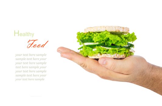 The concept of a healthy food, diet, losing weight, vegeterian. Man's hand holding a healthy burger with wholegrain cereal crispbreads, vegetables, herbs and cheese. Isolated on white background