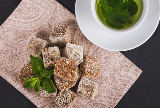 Sweets for raw foodists on a beautiful background with mint tea in a white cup on a white saucer