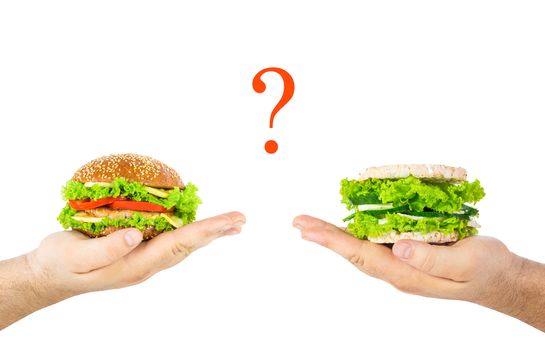 concept of choosing harmful junk food or natural health food. A man's hands holding  classic burger and healthy burger with wholegrain cereal crispbreads, vegetables, herbs and cheese. Question mark. 