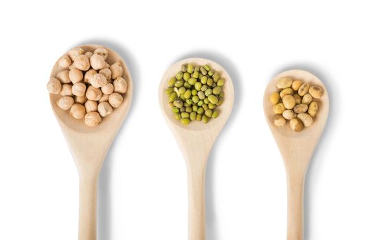 Different types of legumes in a wooden spoons isolated on white background: soybeans, mung beans and chickpea 