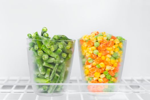 Frozen vegetables and legumes in the freezer, green beans, corn green peas and chopped carrots