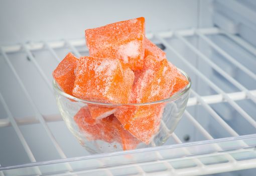 Sliced frozen pumpkin in the freezer in a transparent piala