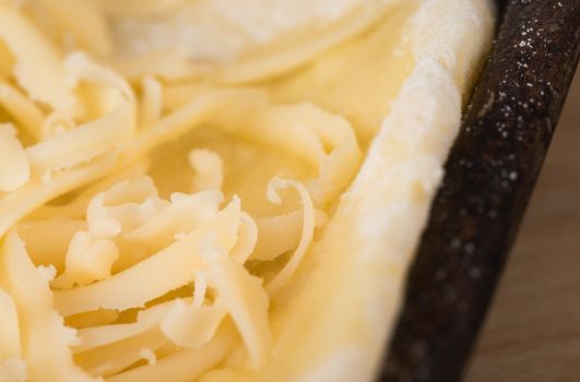 Grated cheese on a baking sheet close up, cooking pizza