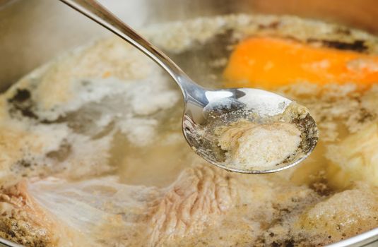 iron spoon removes the foam from meat broth