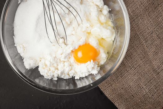 The ingredients for homemade baking cheesecake, a wheat flour, egg, sugar in a bowl, whisk, top view