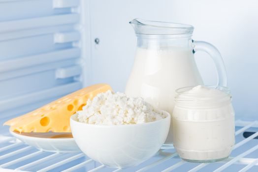 tasty healthy dairy products in the refrigerator: sour cream in the bank, cottage cheese in  bowl,  cheese  and milk in a jar