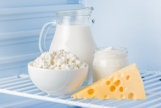 tasty healthy dairy products in the refrigerator: sour cream in the bank, cottage cheese in  bowl,  cheese  and milk in a jar