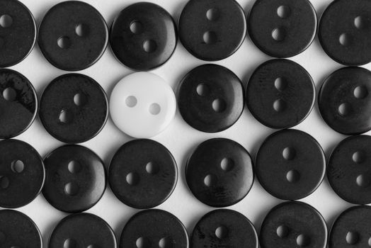 several rows of black buttons on a white background, among them the one white, stands out concept, to be bright, special, individual, not like everyone, not like the others, life style