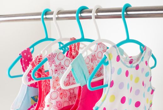 row of bright colorful little girl dresses hanging on coat hanger in white wardrobe