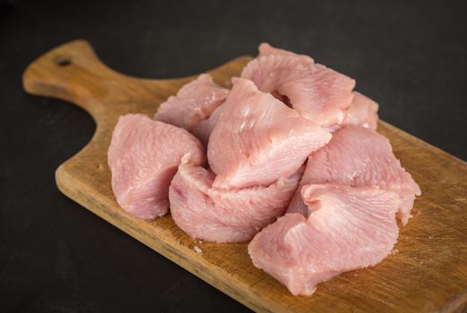 Raw fresh minced turkey meat on a wooden cutting board on a dark background