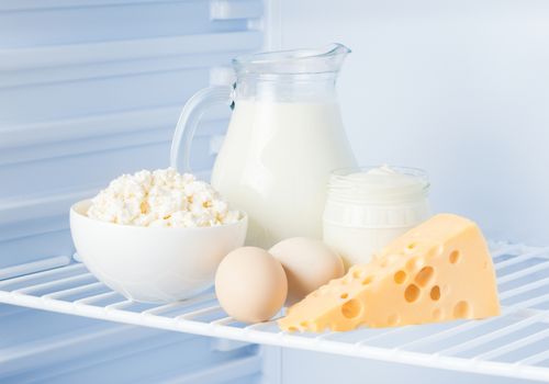 eggs and tasty healthy dairy products in the refrigerator: sour cream in the bank, cottage cheese in  bowl, eggs, cheese  and milk in a jar