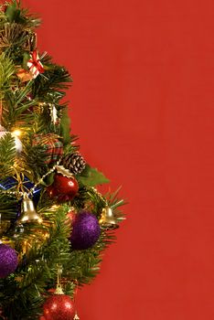 Vertical shot of a decorated Christmas tree on a red background