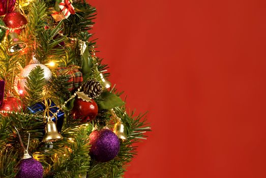 Horizontal shot of a beautiful little Christmas tree on a red background with lots of copy space.