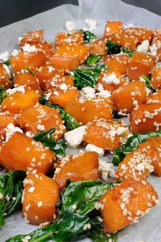 Slices of pumpkin baked with spinach and sesame seeds  