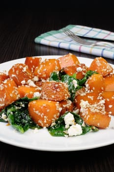 Slices of pumpkin baked with spinach and sesame seeds