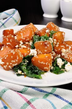 Slices of pumpkin baked with spinach and sesame seeds