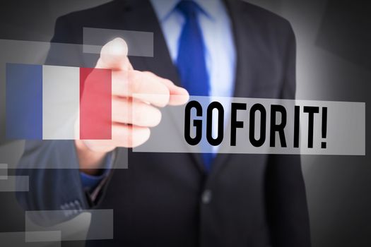 The word go for it! and businessman pointing his finger at camera against abstract grey room