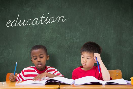 The word education and cute pupils writing at desk in classroom against green chalkboard