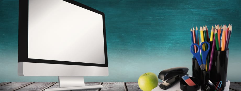 School supplies on desk against green chalkboard