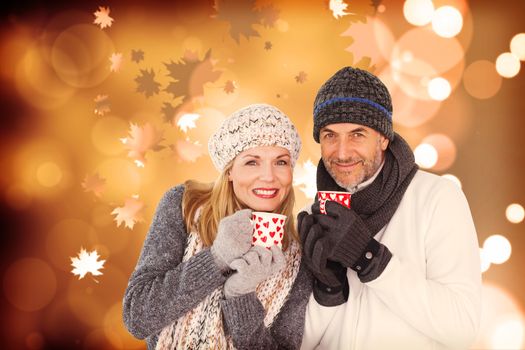 Portrait of couple drinking hot coffee against autumnal leaf pattern