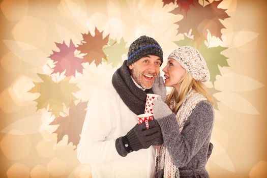 Happy couple gossiping while drinking hot tea against autumnal leaf pattern in warm tones