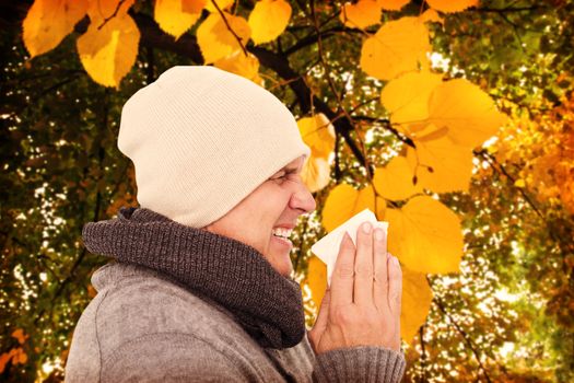 Casual man about to sneeze against autumnal leaves against plants