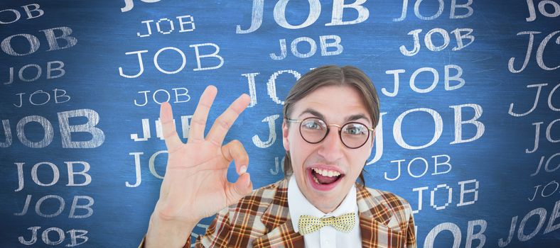 Geeky hipster doing the ok sign against blue chalkboard