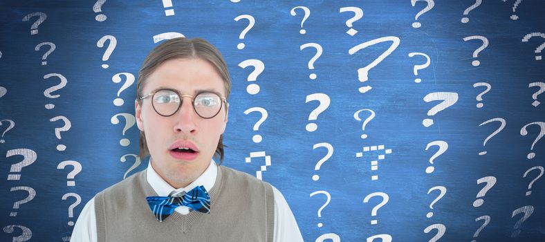 Geeky hipster looking surprised at camera  against blue chalkboard