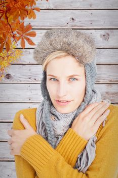 Woman in winter clothes shivering over white background against autumn leaves pattern