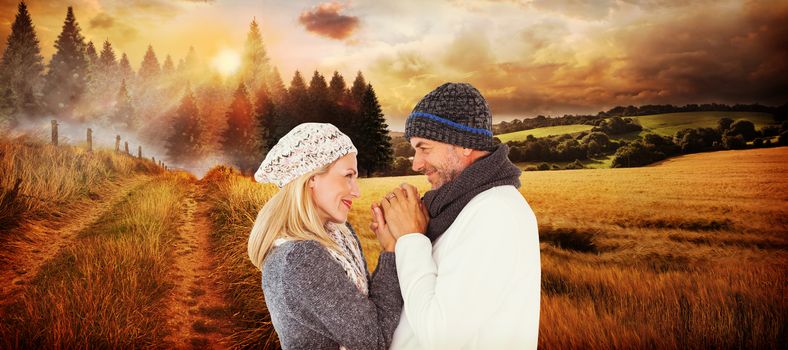 Cute smiling couple holding hands against country scene