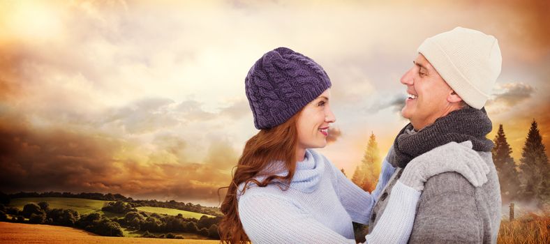 Happy couple in warm clothing against country scene