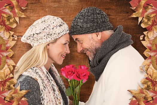 Cute couple holding rose while looking at each other against overhead of wooden planks